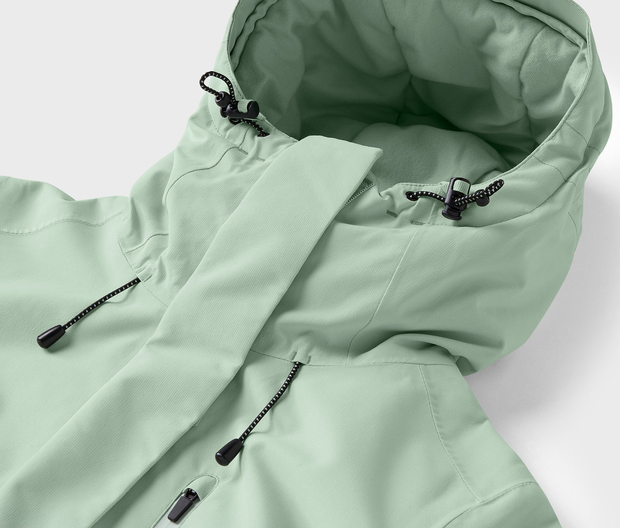 Világoszöld kabát részlete kapucnival és húzózsinórokkal.