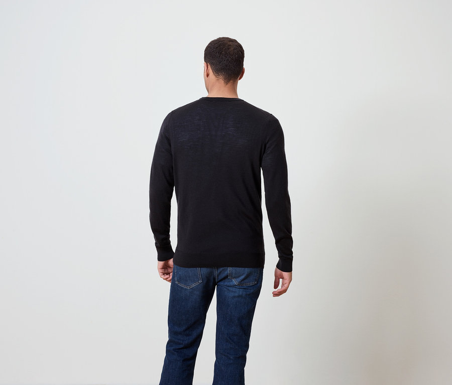 Hátulról látható férfi, sötét pulóvert és farmert visel.