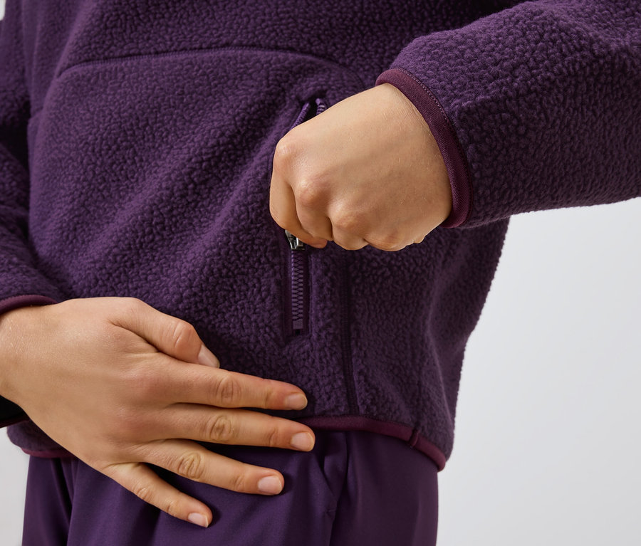 Egy személy cipzárral zárja a lila fleece pulóvert.