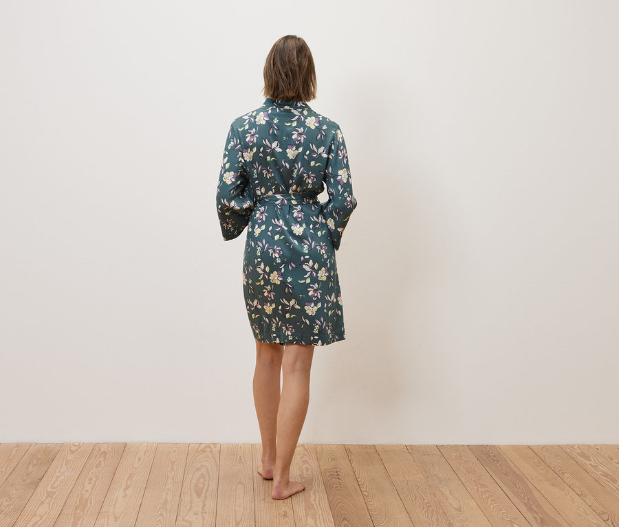 Nő áll háttal, virágos köntöst visel.