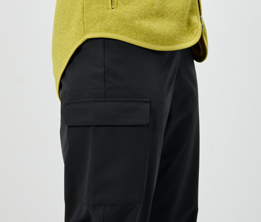 Fekete nadrág zsebbel és sárga kabát.