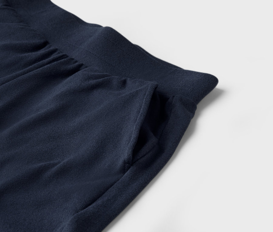 Egy sötétkék színű, zsebes jogging alsó részlete fehér háttérrel.