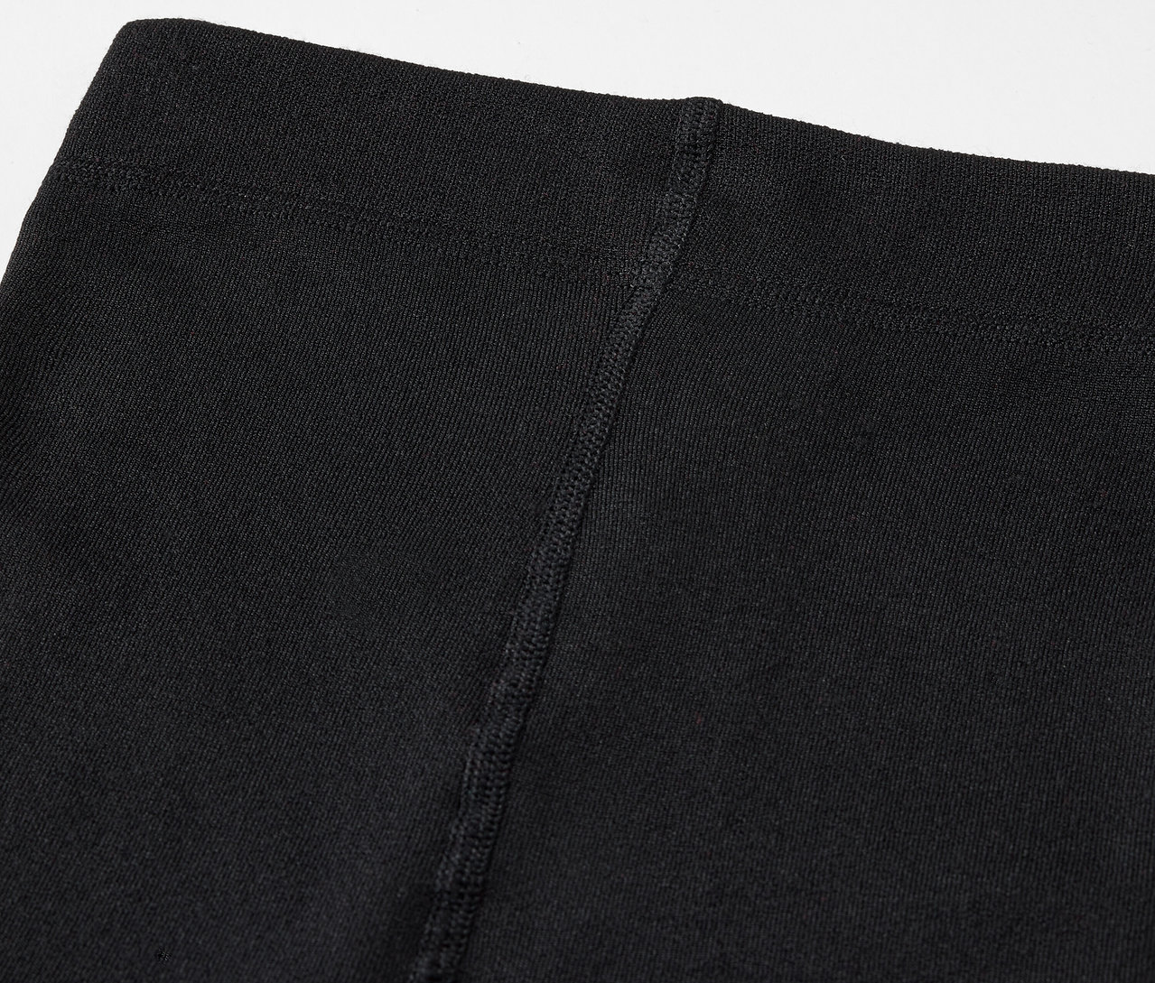Közeli felvétel egy fekete leggings felső részéről, látható varrással.