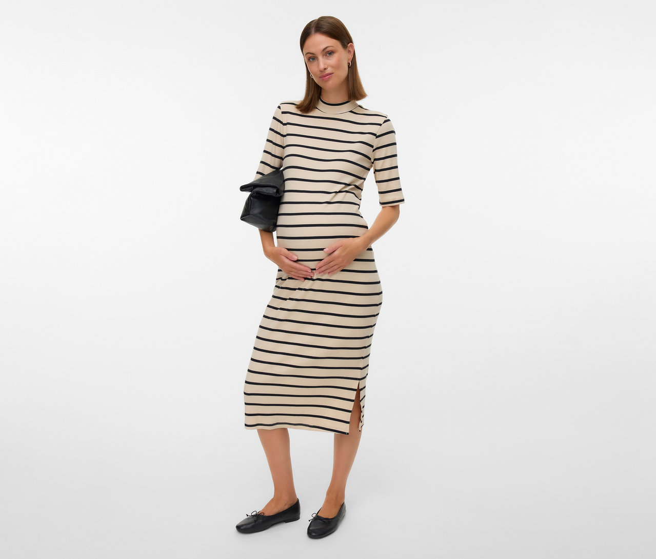 Terhes nő MAMALICIOUS csíkos kismama midiruhában, fekete táskát tart, fekete balerinát visel.