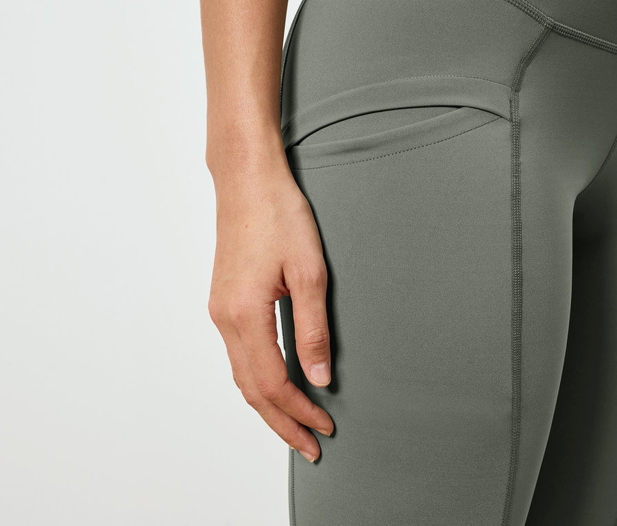 Egy személy közelképe olívazöld leggingsben, oldalzsebbel.