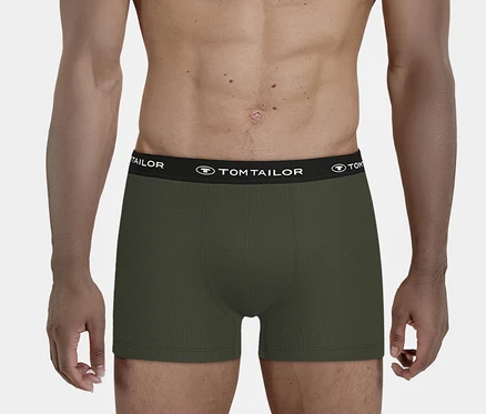Férfi visel sötétzöld, bordázott boxeralsót fekete TOM TAILOR feliratos derékpánttal, deréktól felfelé látható.