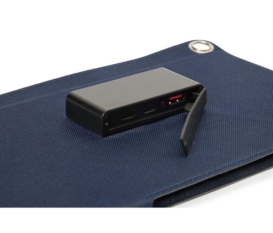 Fekete akkumulátor fekszik egy kék szövet felületen, látható USB porttal.