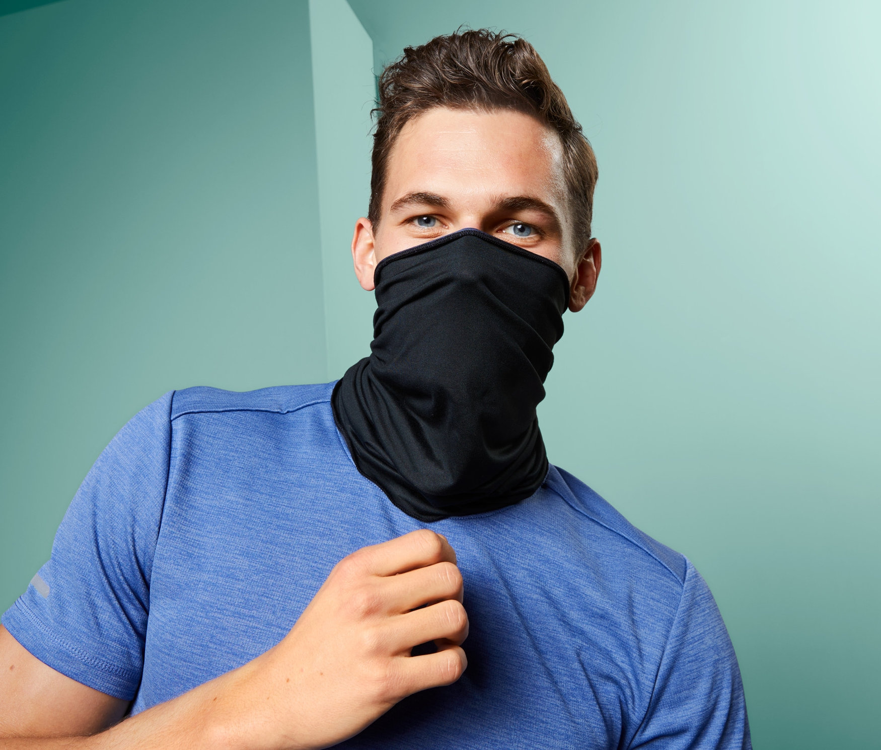 Barna hajú férfi kék pólót visel, a száját és orrát eltakaró fekete multifunkcionális csősállal.