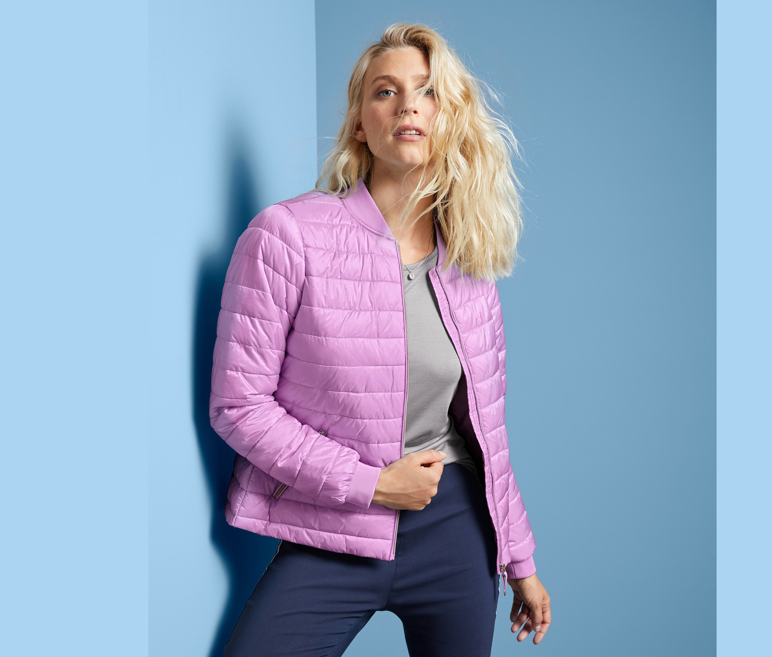 Nő pózol steppelt kabátban.