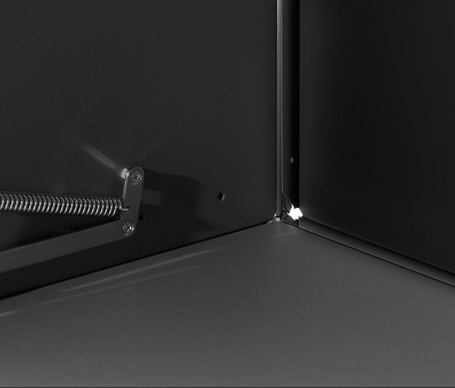 A fekete »CN3« szekrény belsejének részlete, a sarokra és a nyitószerkezetre fókuszálva.