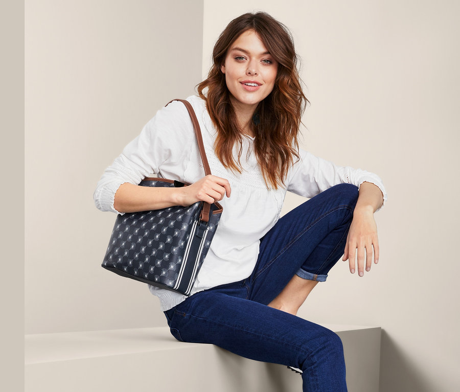 Nő ül és egy kék női oldal-és válltáskát tart.