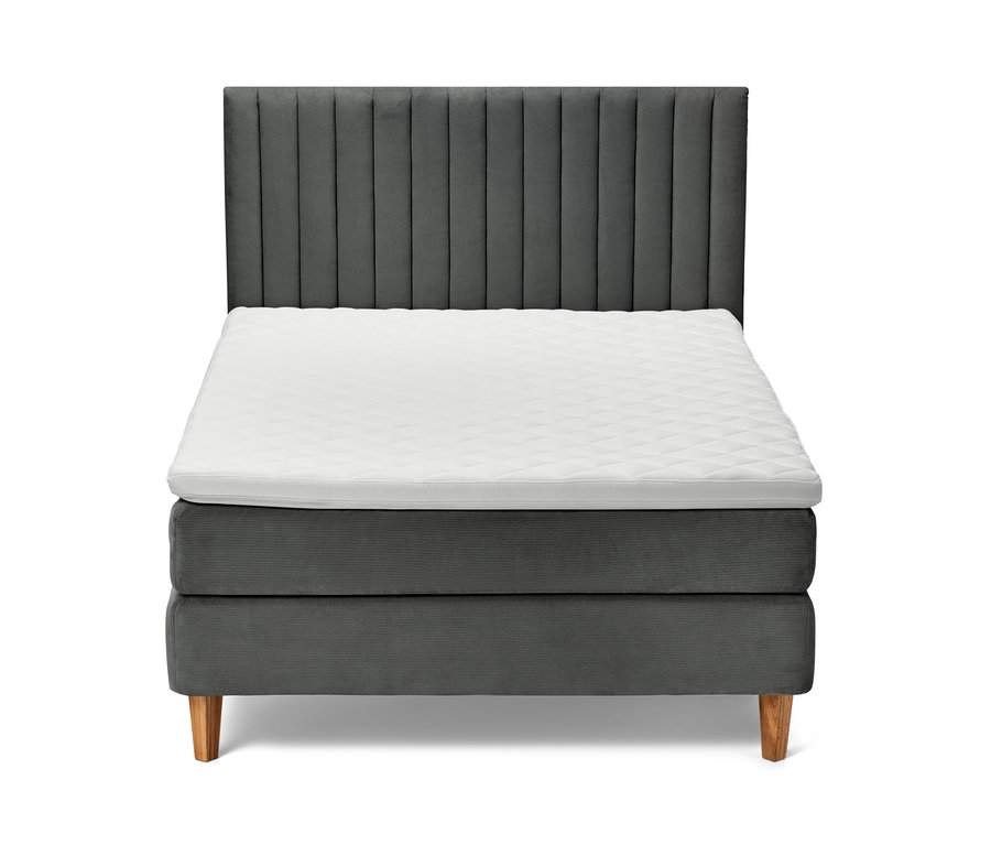 Antracit boxspring ágy fehér matraccal és fa lábakkal.