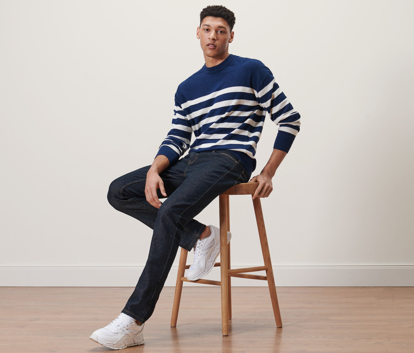 Egy férfi ül egy széken és farmert visel.