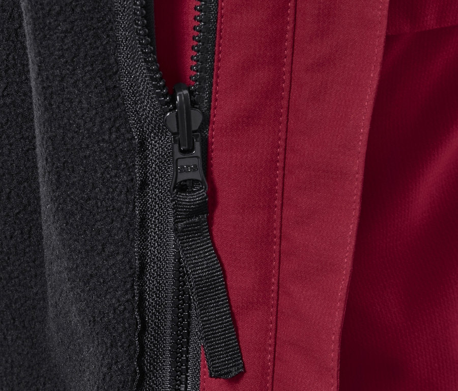 Egy outdoor kabát cipzárjának részlete fekete fleece béléssel és piros külső anyaggal.