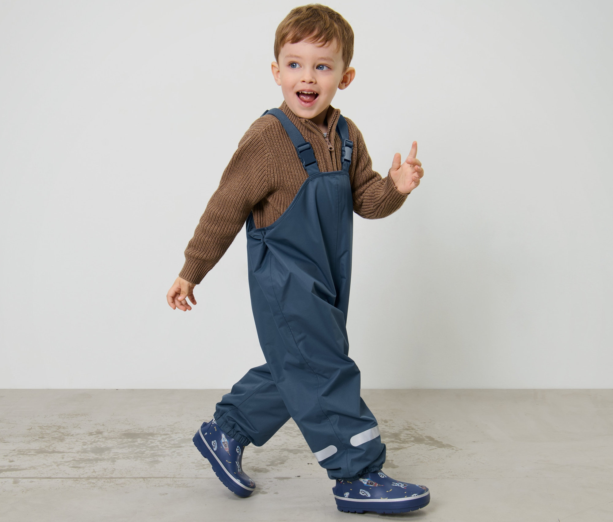 Fiú sétál, sötétkék gyerek termo esőnadrágot visel.
