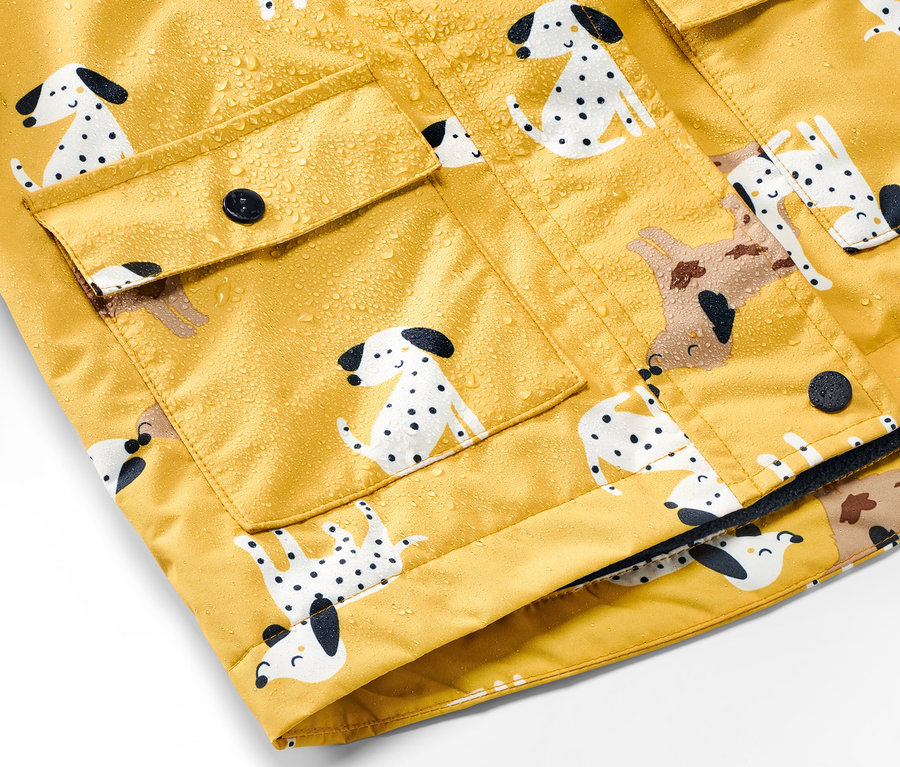 Egy sárga, dalmata mintás gyerek termo esőkabát részlete vízcseppekkel.