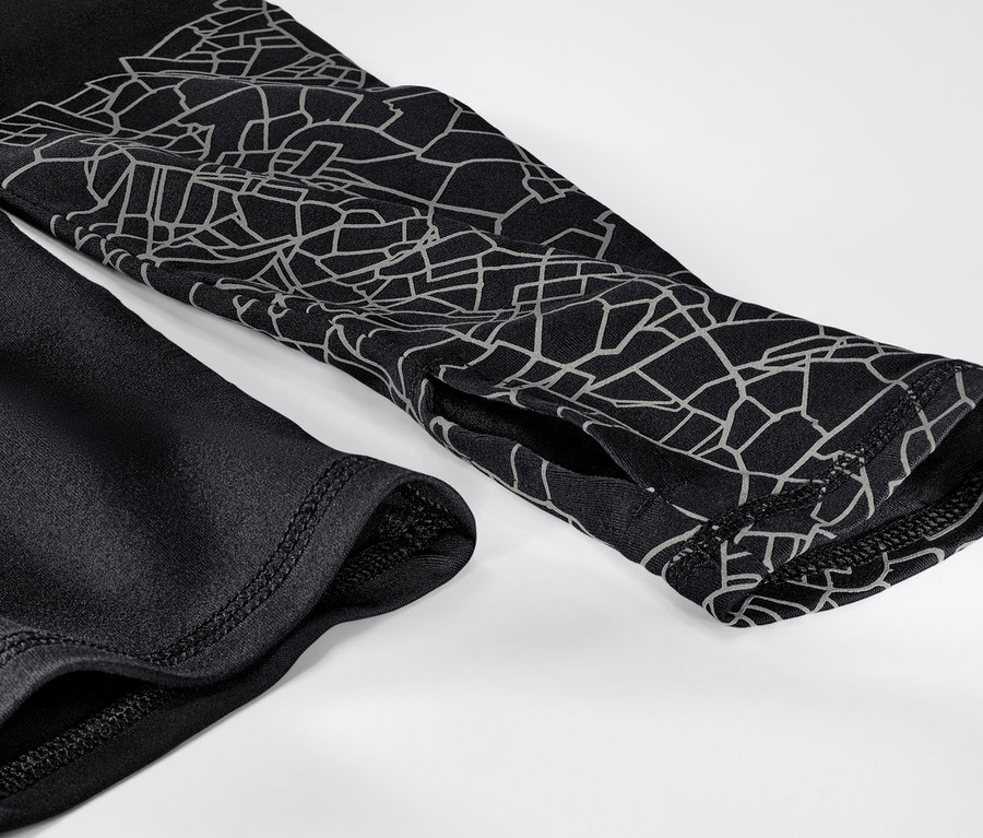 Egy fekete-ezüst színű, hosszú ujjú funkcionális felső részletének közeli képe.