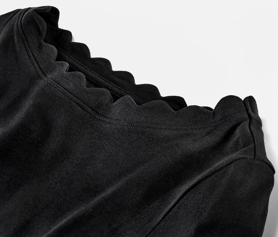 Egy fekete, háromnegyedes ujjú, csipkés nyakú női felső részletfotója.