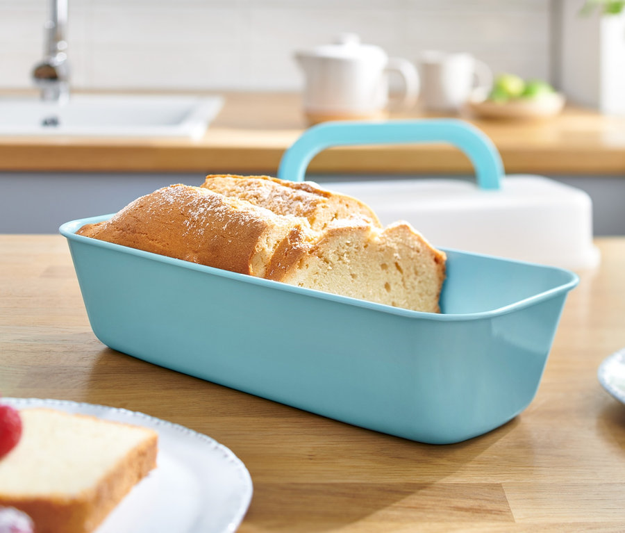 Szeletelt kenyér egy fedeles sütőformában egy fa asztalon.