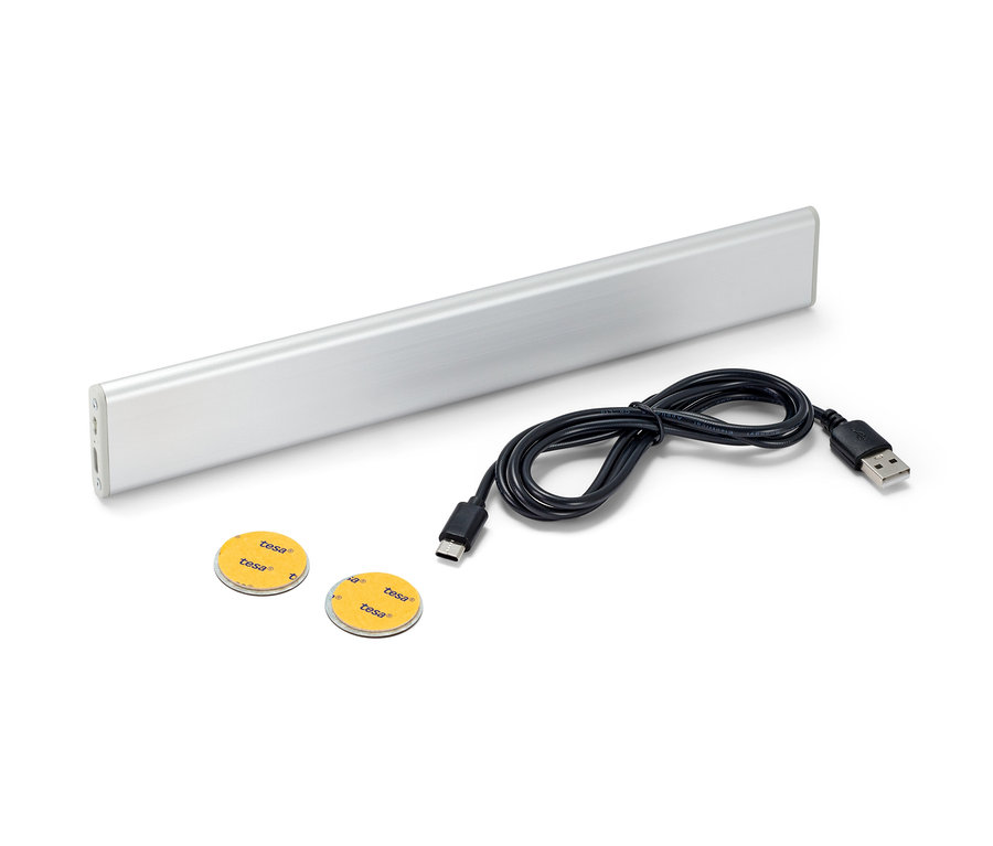 Egy multifunkciós LED-es lámpa, egy fekete kábel és két ragasztópárna fehér háttéren.