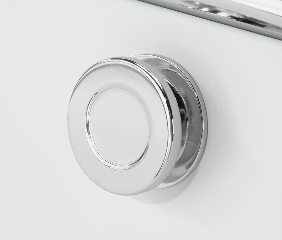 Közelkép egy fehér »CN3« komódról, kerek króm fogantyúval és egy króm rúddal felette.