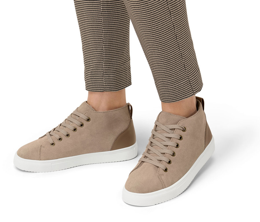 Egy személy lábai kockás nadrágban, plüssbéléssel ellátott velúrbőr sneaker cipőben.
