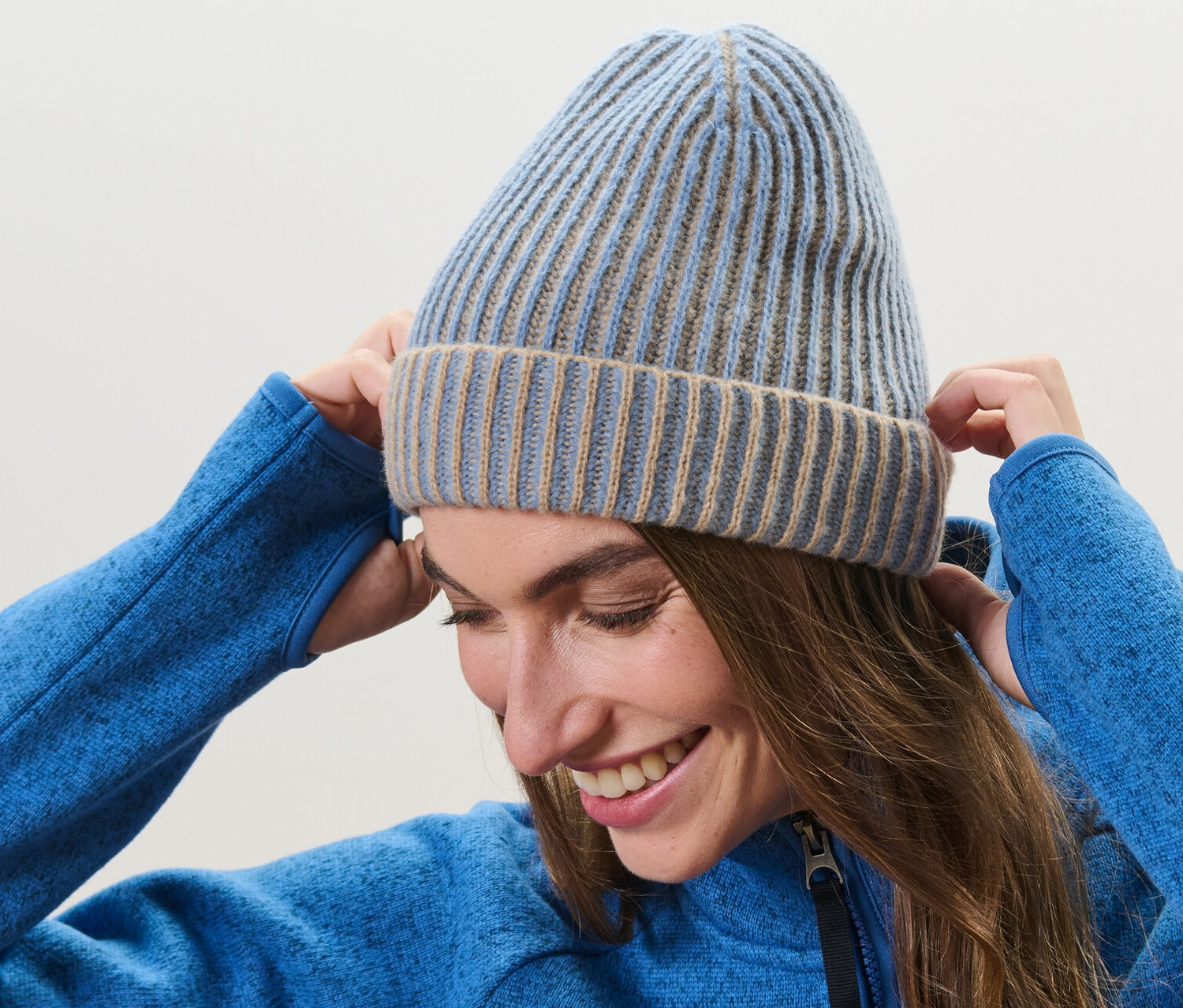 Nő igazgatja a kötött sapkáját a fején.