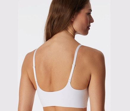 Hátulnézet egy barna hajú nőről, aki fehér SCHIESSER láthatatlan betétes bustier melltartót visel.