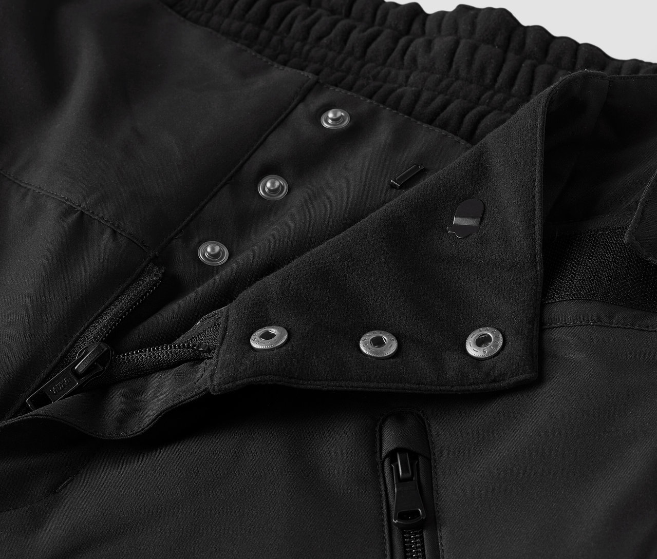 Fekete szövet részlete gombokkal és cipzárral.