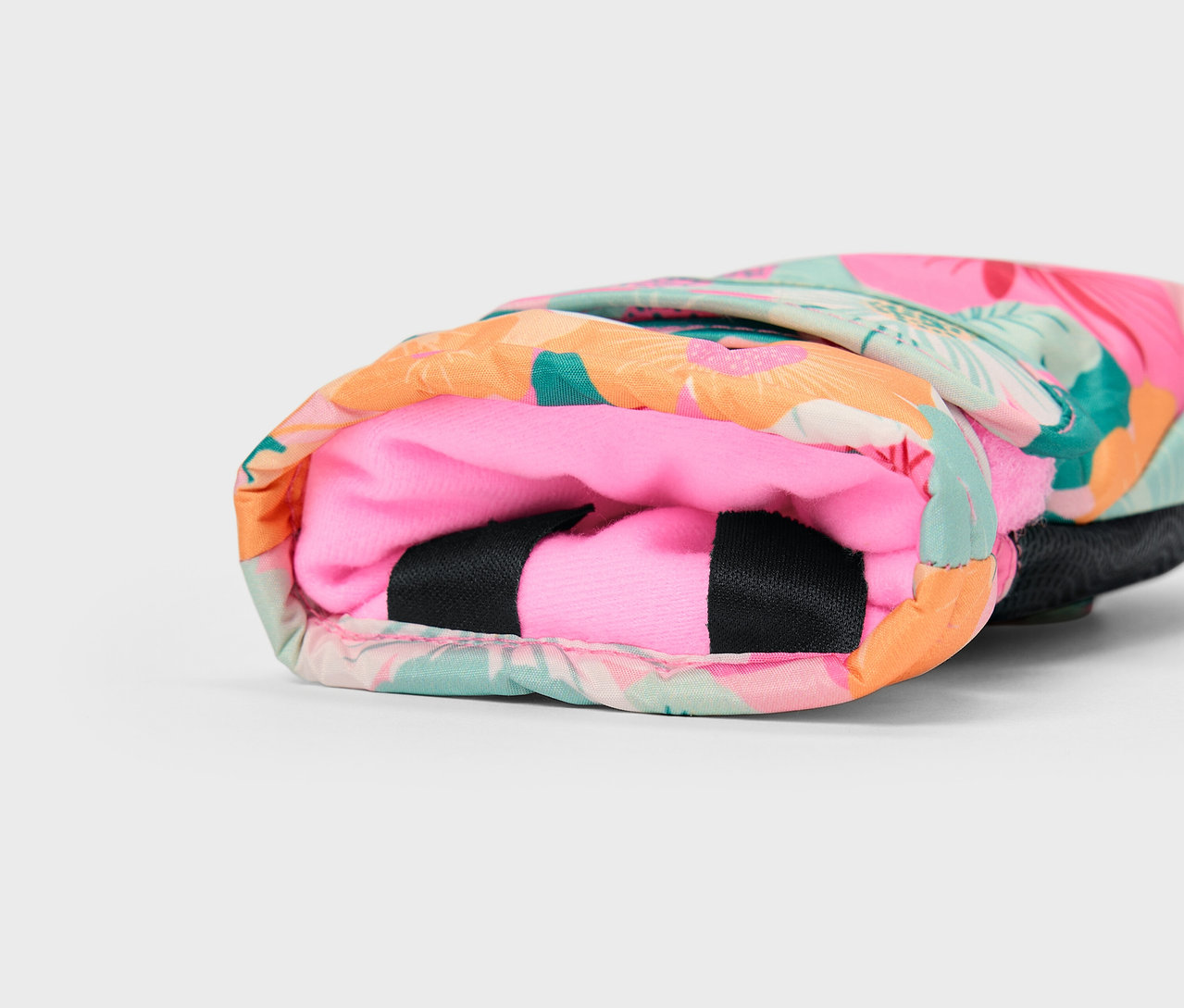 Egy színes, trópusi mintás borító részlete rózsaszín béléssel.