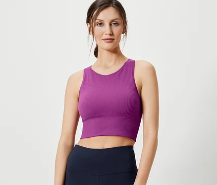 Nő pózol varrásmentes sportmelltartóban és sötétkék leggingsben.