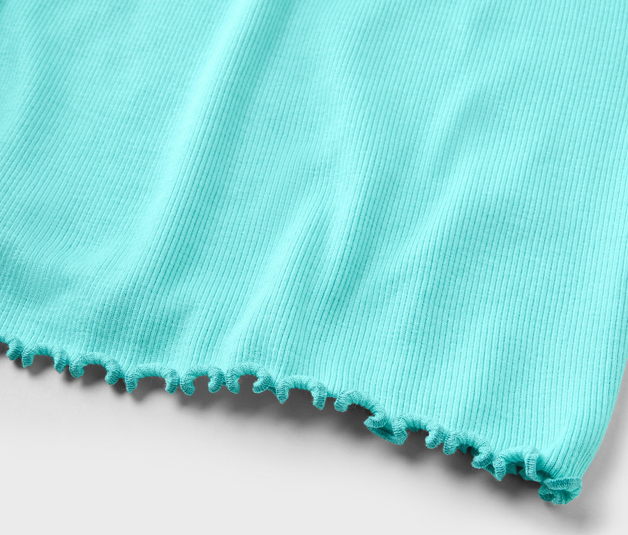 Egy világoskék, rövidnadrágos, bordázott anyagból készült pizsama részletének fényképe.