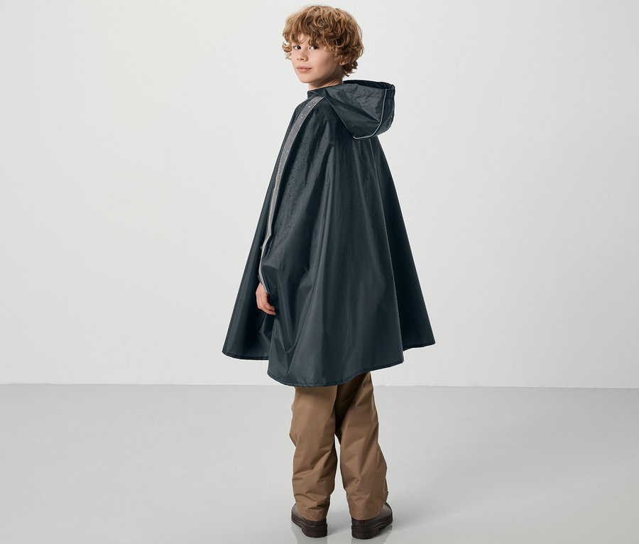 Egy fiú a válla fölött néz hátra, és kék gyerek esőponcsót visel.