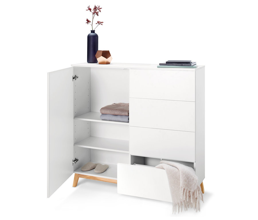 Nyitott, fehér komód polcokkal, ruhákkal, papucsokkal és fiókokkal.