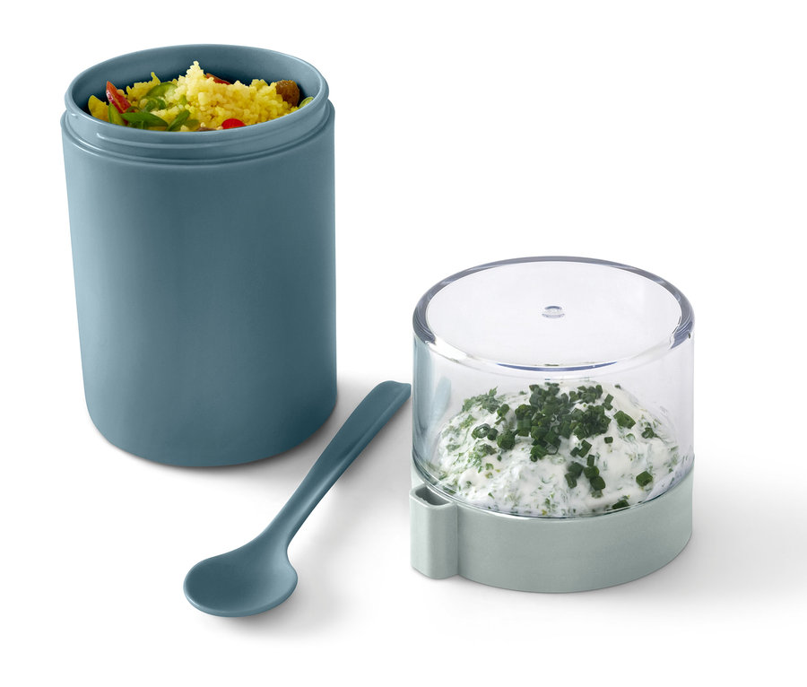 Zöld to-go joghurtos pohár tartalommal, mellette egy kanál és egy edény fűszeres túróval.