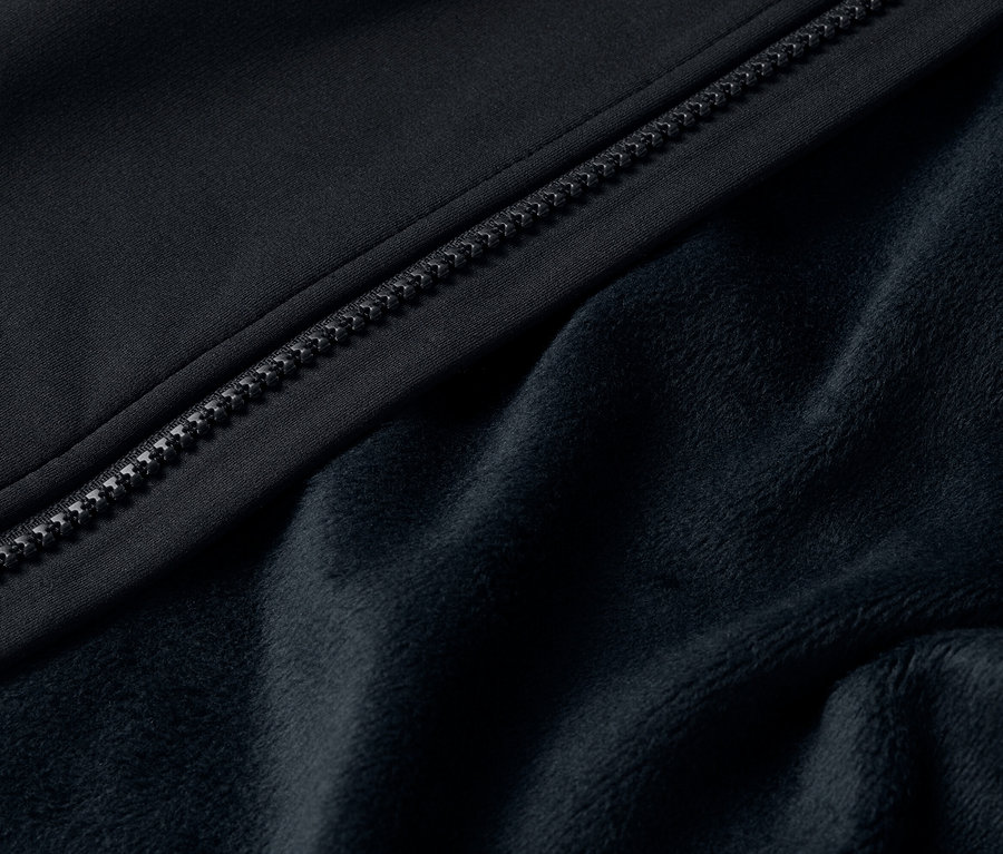 Egy fekete kabát cipzárjának és puha polár bélésének részlete.