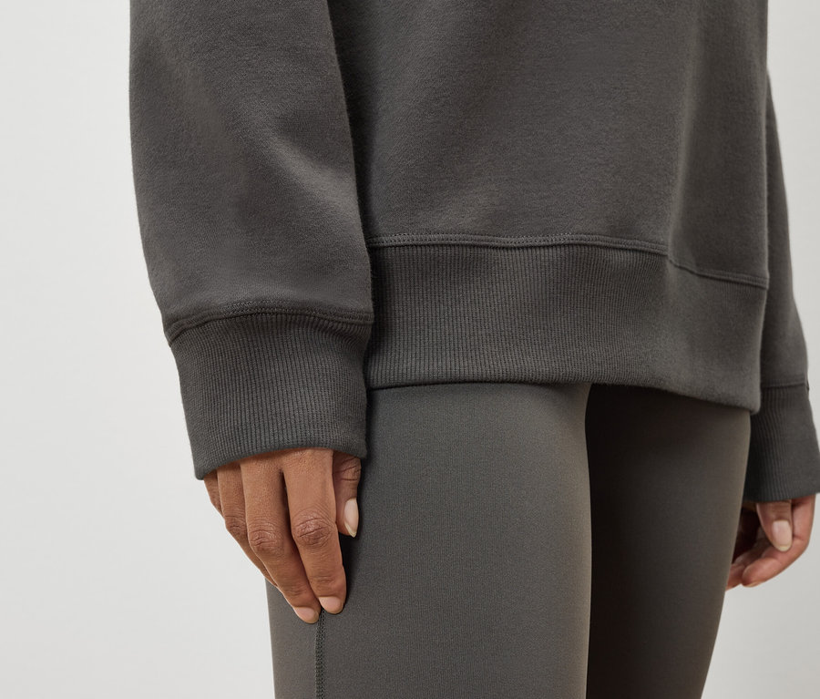 Női szürke pulóver és leggings részlete.