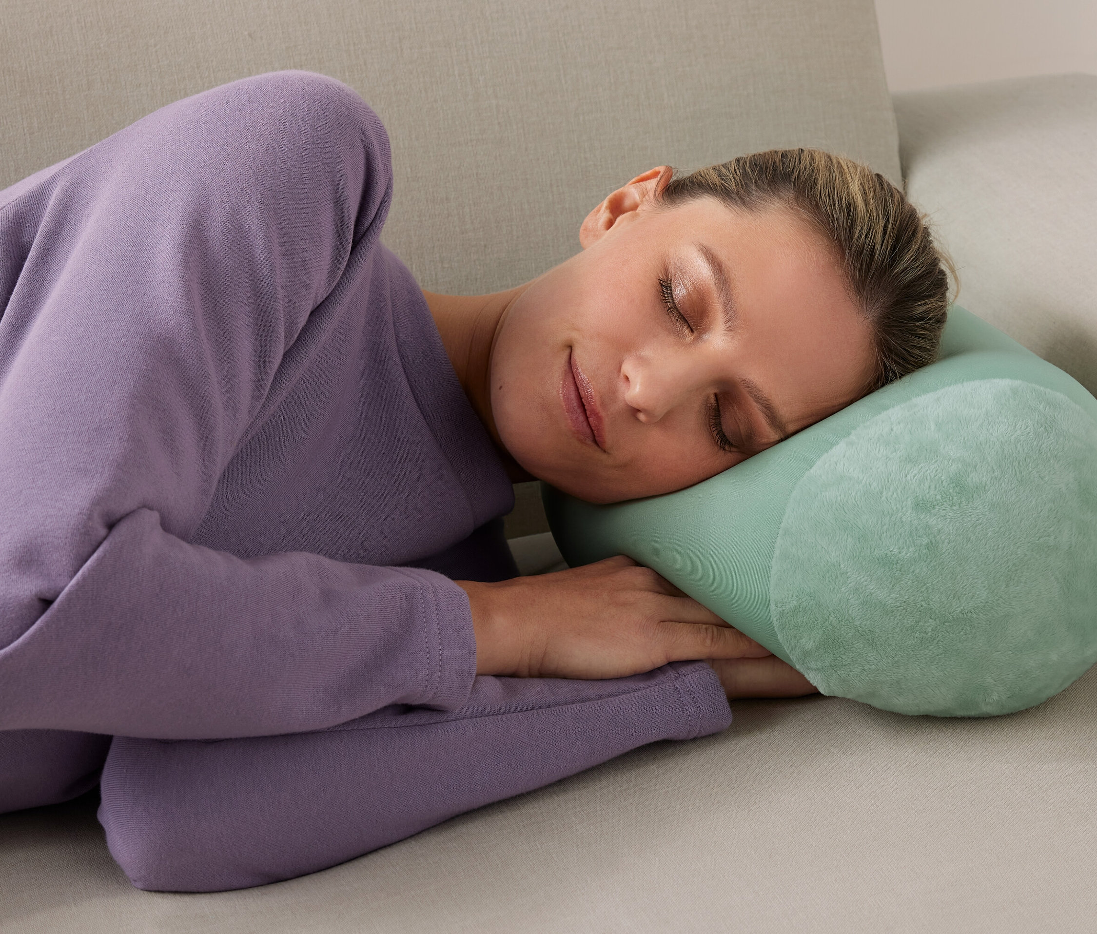 Nő alszik egy relaxkissen párnán a kanapén.