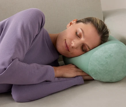 Nő alszik egy relaxkissen párnán a kanapén.