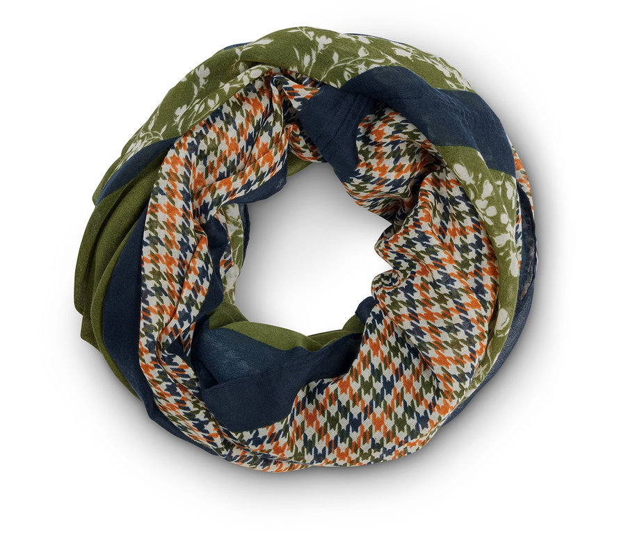 Különböző mintákkal, köztük virágmintákkal, kakaslábmintákkal és zöld és kék színű színblokkokkal ellátott kör alakú sál közeli képe.