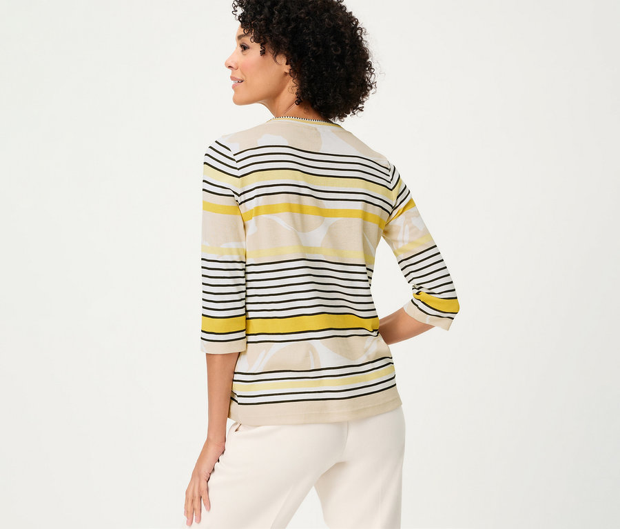 Hátulról látható nő Olsen 3/4-es pólóban, sárga, fekete és bézs csíkokkal és virágmintával.