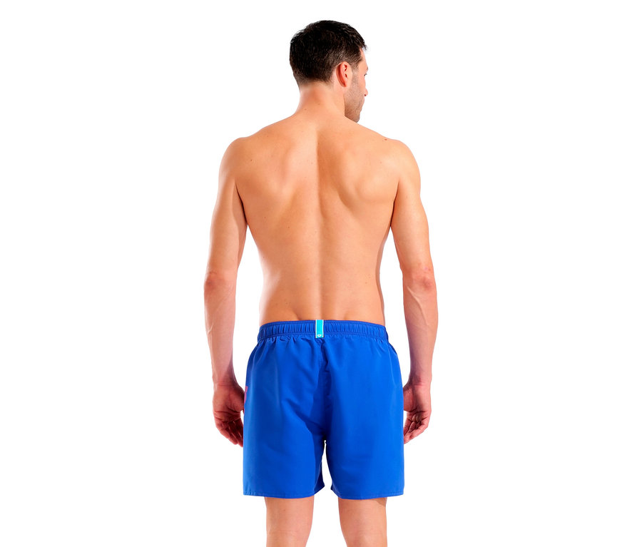 Hátulnézet egy kék fürdőnadrágot viselő férfiról fehér háttérrel.