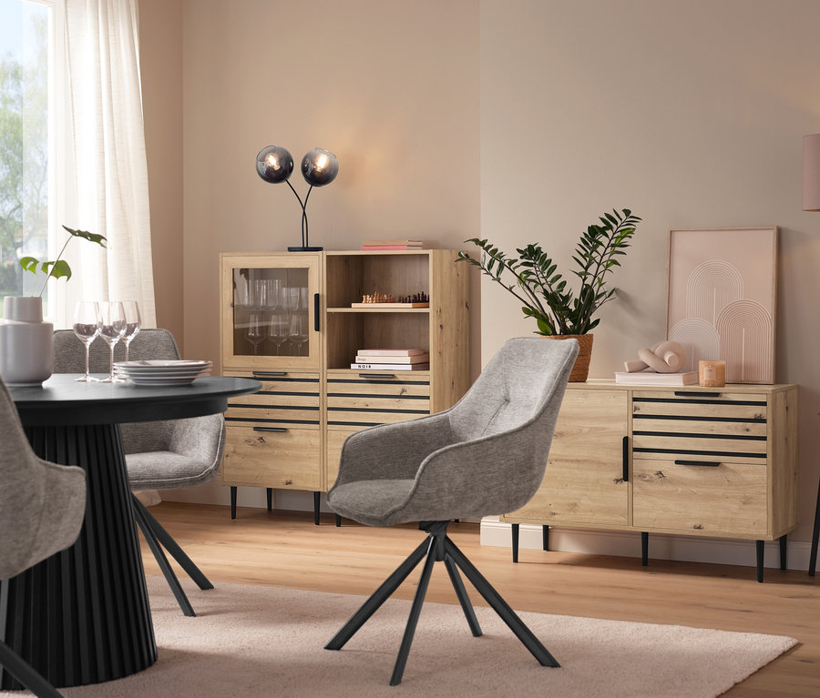 Étkező kerek asztallal, szürke székekkel, egy »BAAKEN« üvegajtós vitrinnel, egy »BAAKEN« fiókos polccal és egy fiókos szekrénnyel.