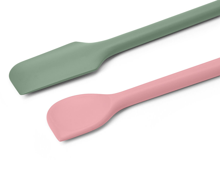 Egy zöld és egy rózsaszín szilikon spatulának a közeli képe fehér háttérrel.