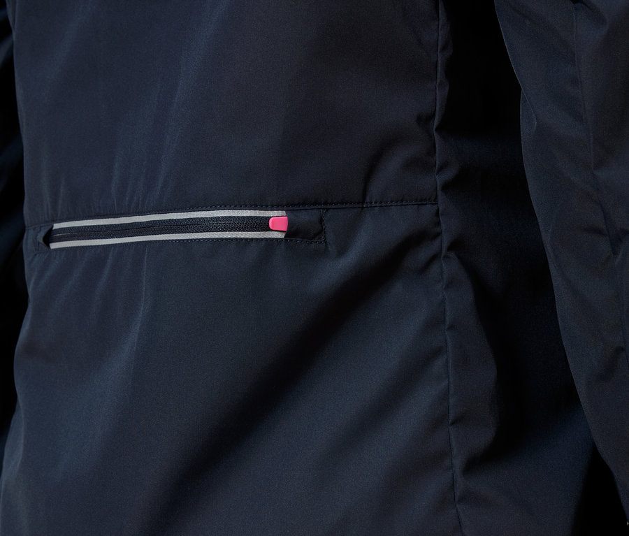 Egy sötétkék kabát részletfotója cipzáras zsebbel, melynek cipzárja rózsaszín hangsúlyú.