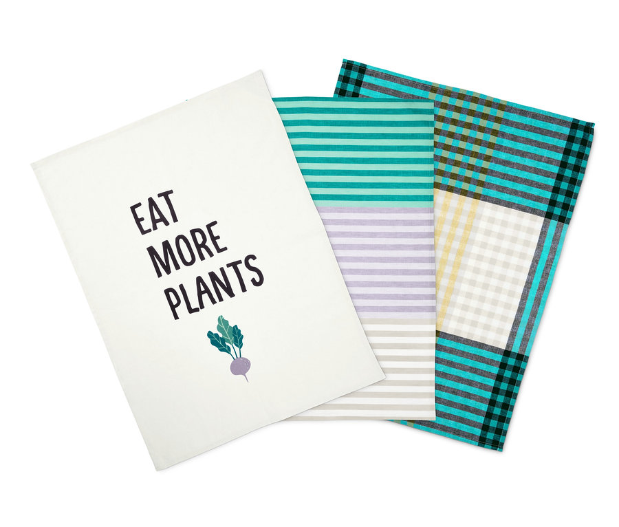 Három konyharuha: egy fehér, "Eat More Plants" felirattal, egy csíkos és egy kockás.