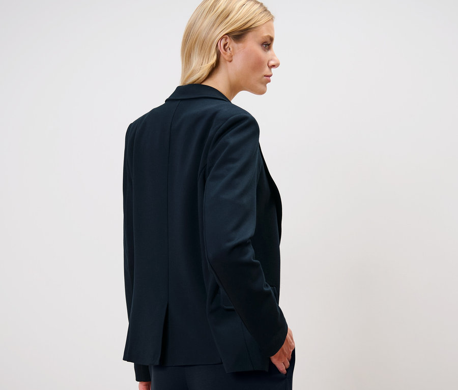 Szőke nő jersey blézerben.