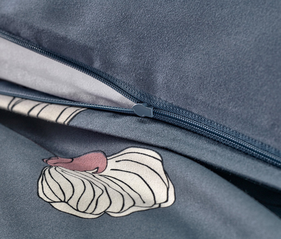 Egy sötétkék, virágmintás mikroszálas ágynemű cipzárjának közeli képe.