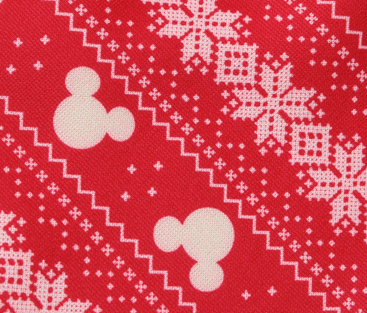 Mintás piros szövetfelület fehér hópihékkel és Mickey egér motívumokkal.