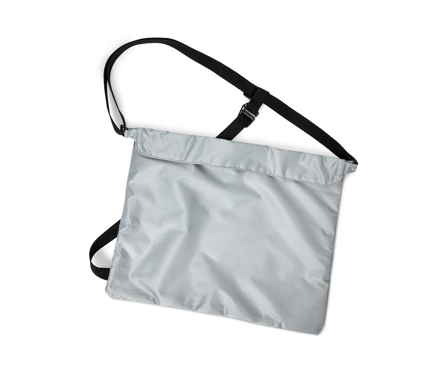 Ezüstszínű kerékpáros bevásárlótáska függőleges felvétele fekete pántokkal fehér háttér előtt.